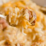 Cheesy baked rice casserole with bacon and vegetables, served on a spoon, close-up. Delicious comfort food featuring melted cheese, crispy bacon, and flavorful rice, perfect for a hearty meal.