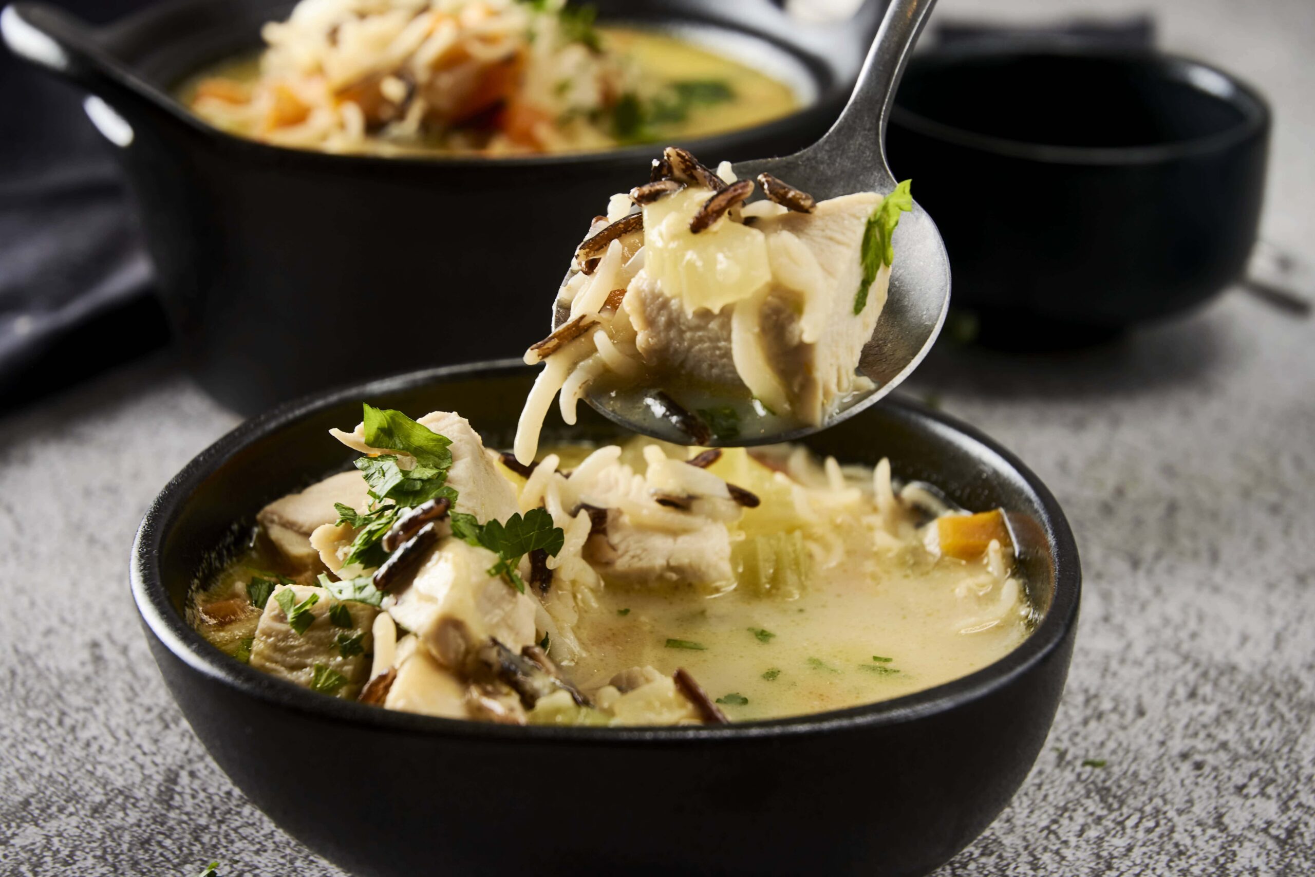 Creamy chicken and mushroom soup served in a black bowl with fresh herbs and noodles, ready to enjoy for a comforting meal.