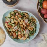 Fresh cucumber and radish salad with crispy pita chips and herbs, served in a white bowl for a healthy, delicious meal.