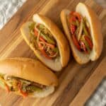 Steamed bao buns filled with colorful stir-fried vegetables including bell peppers and onions, served on a wooden cutting board for a delicious and healthy Asian-inspired dish.