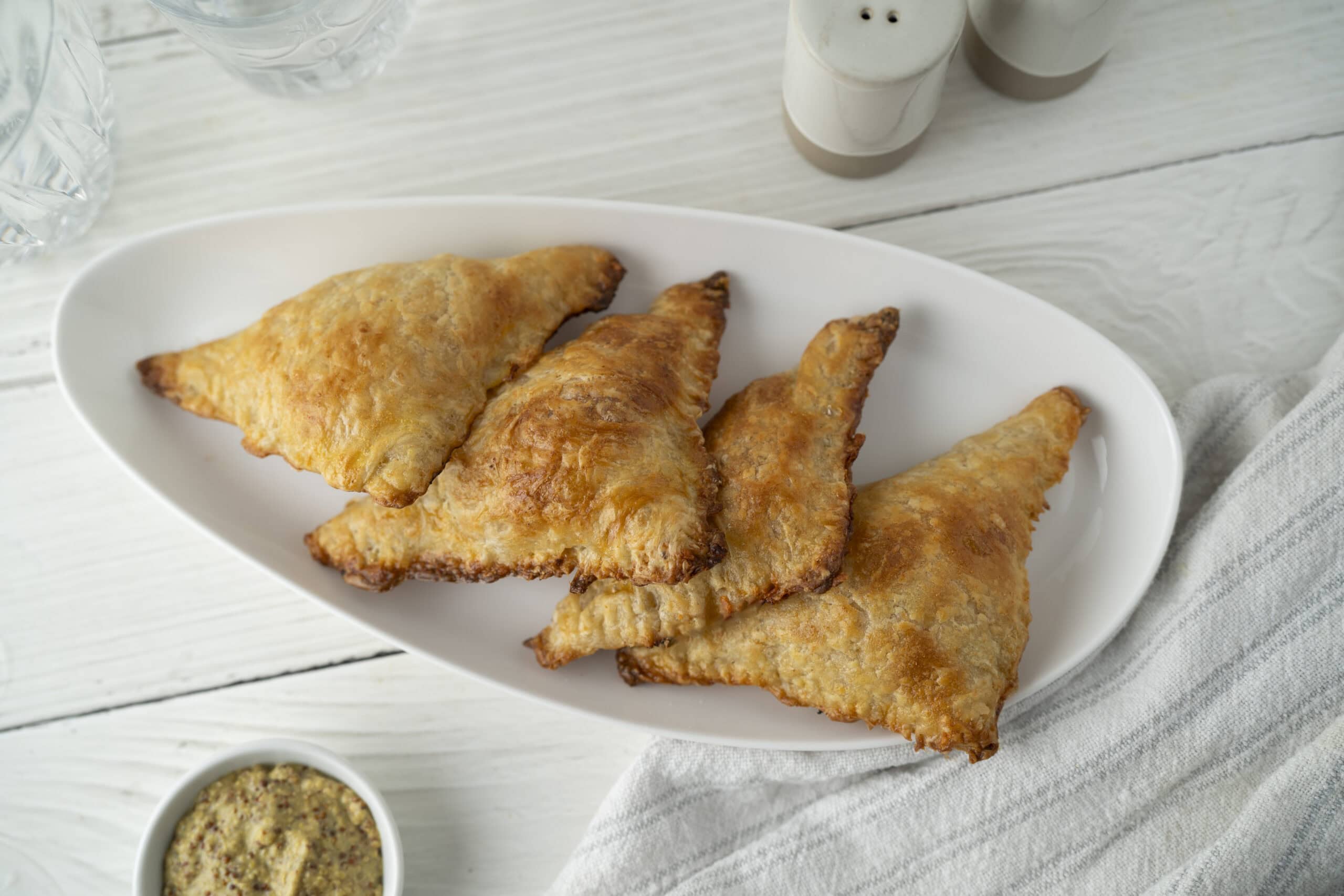 Crispy fried chicken wings served on a white oval platter with a side of dipping sauce, perfect for finger-food or party appetizers.