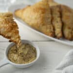 Golden fried chicken served with a side of spicy mustard dipping sauce on a white plate.