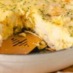 Fluffy baked potato casserole with melted cheese and herbs in a baking dish.