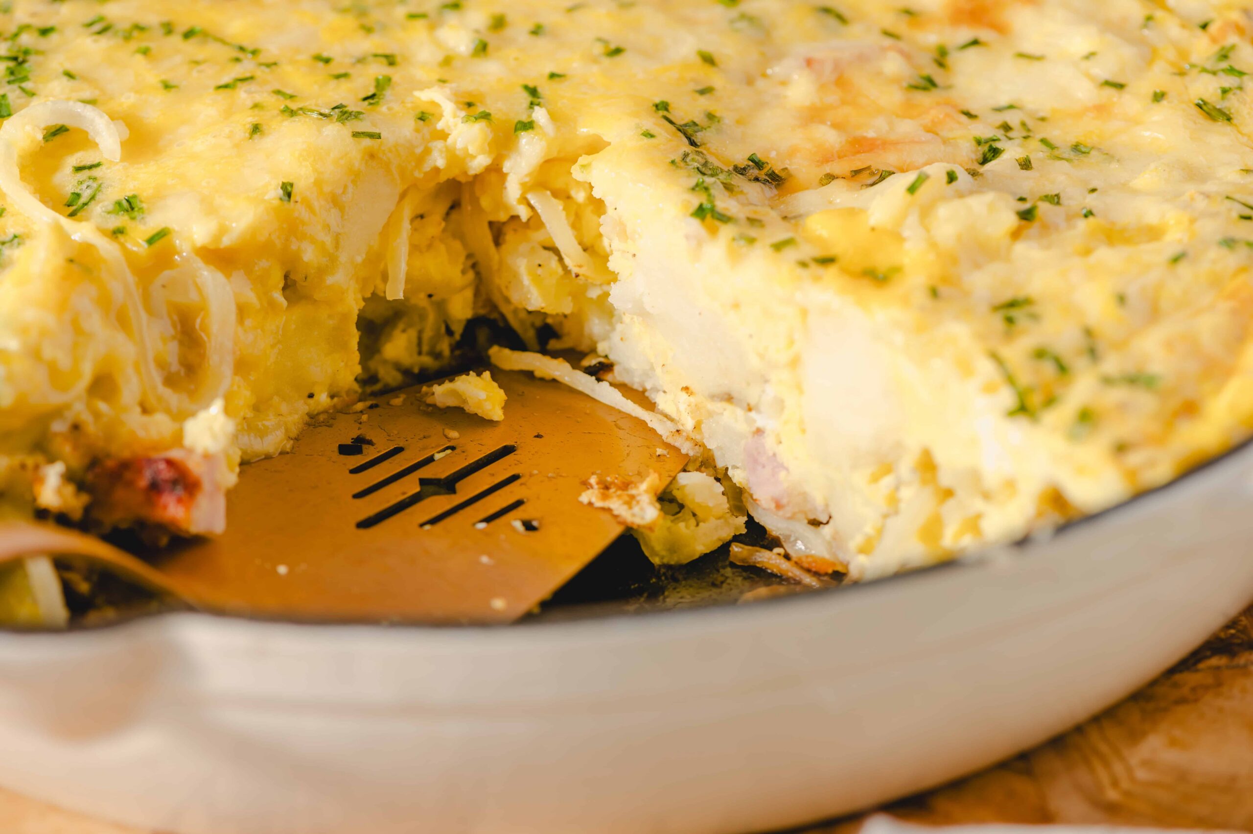 Fluffy baked potato casserole with melted cheese and herbs in a baking dish.