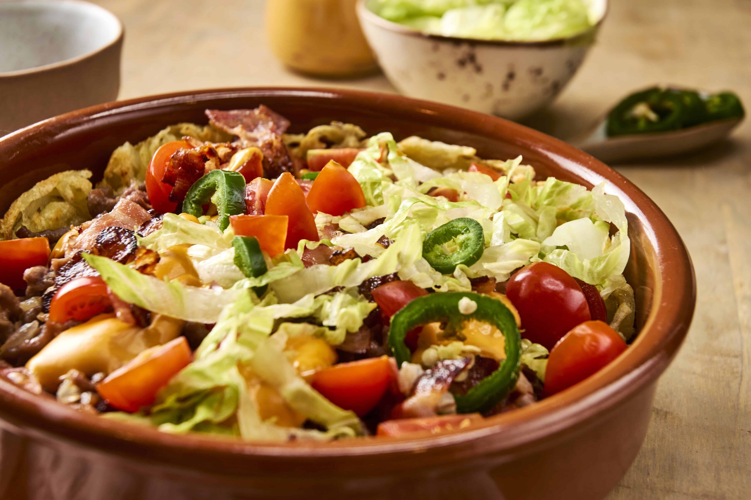 Fresh vegetable salad with cherry tomatoes, cucumbers, lettuce, and sliced peppers in a rustic ceramic bowl. Perfect for healthy eating and meal ideas.