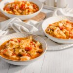 Creamy homemade cabbage soup with beans and vegetables served in white patterned bowls, perfect for a comforting meal.