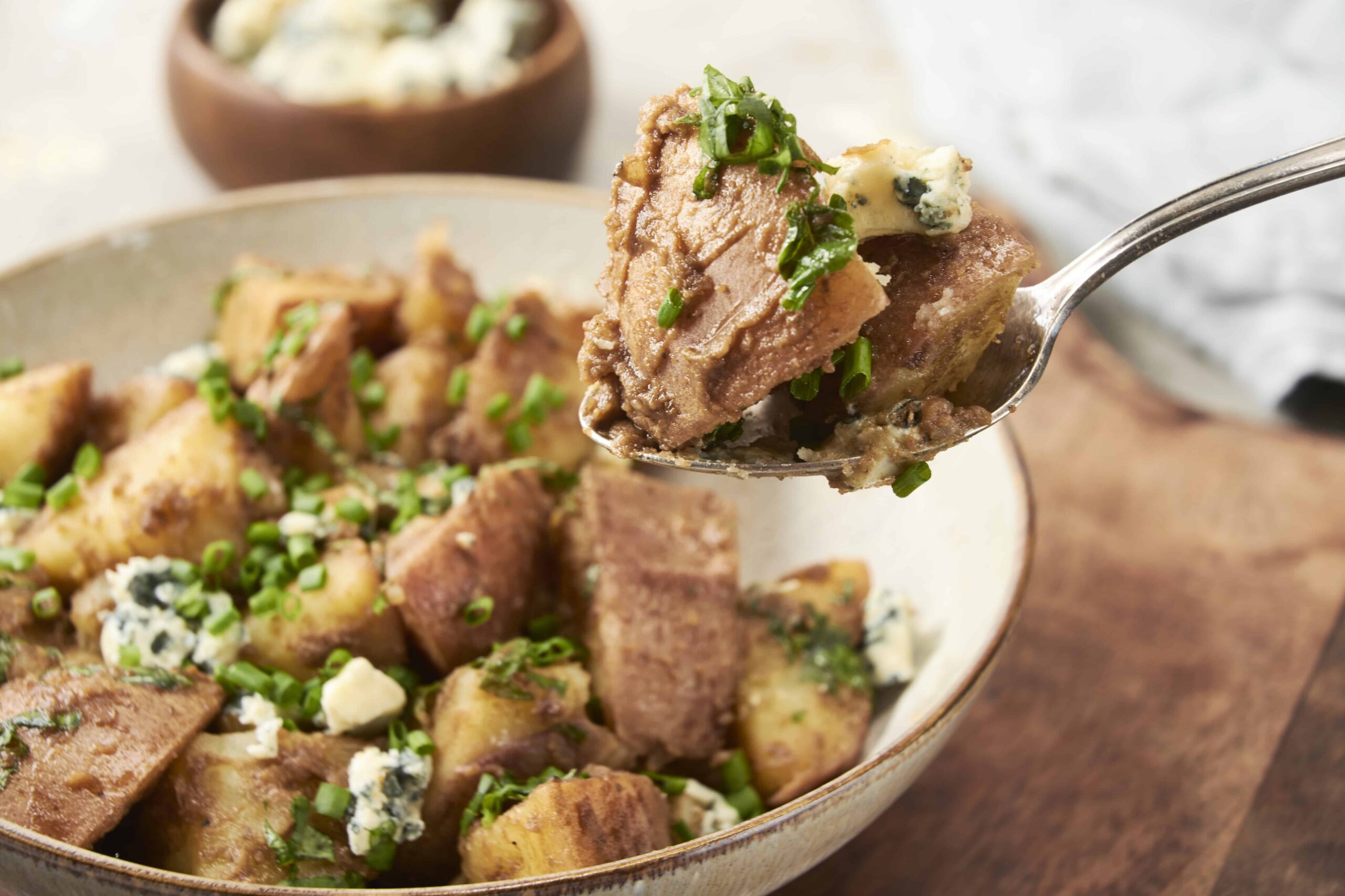 Creamy beef stroganoff with tender potatoes, garnished with fresh chives and blue cheese crumbles. Perfect comfort food recipe with rich, savory flavors.
