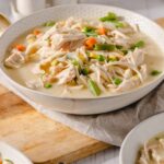 Tender chicken and mixed vegetables in a creamy broth, served in white bowls, perfect for comfort food and healthy eating, featuring carrots, green beans, peas, corn, and shredded chicken.