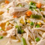 Creamy chicken and vegetable soup with shredded chicken, peas, carrots, and green beans in a rich broth, perfect for cozy homemade meals and easy to prepare.