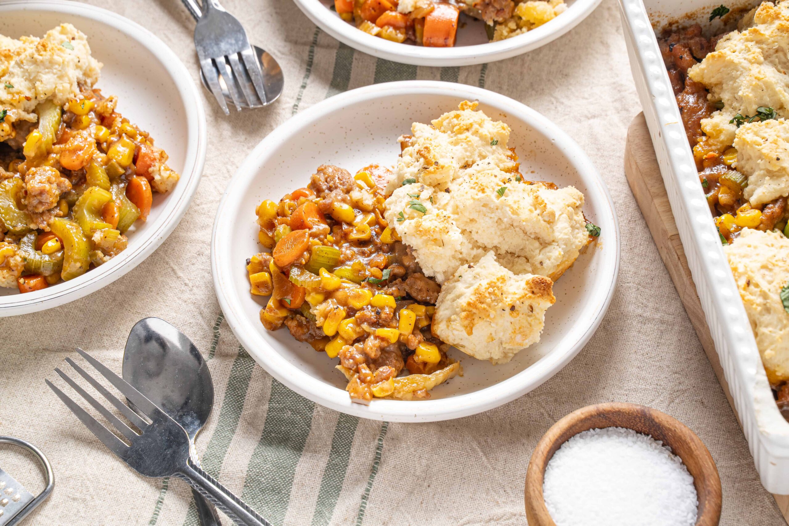 Creamy cheesy mashed potatoes served with hearty beef and vegetable stew on white plates, cozy rustic table setting, perfect comfort food, home-cooked meal, warm and inviting.