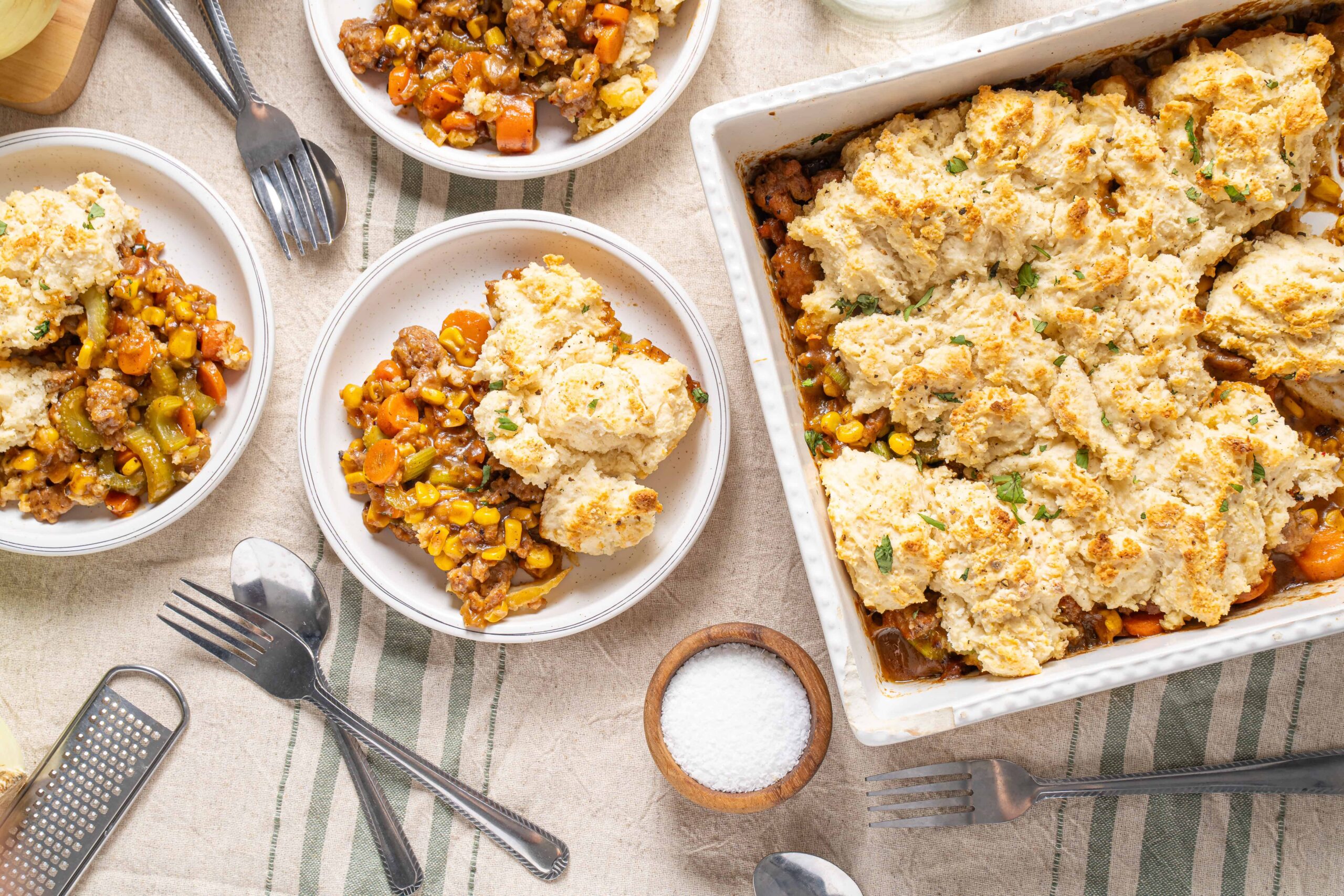 Creamy shepherd's pie topped with mashed potatoes, served alongside vegetable beef stew in white bowls, garnished with herbs. Perfect comfort food for family dinners.