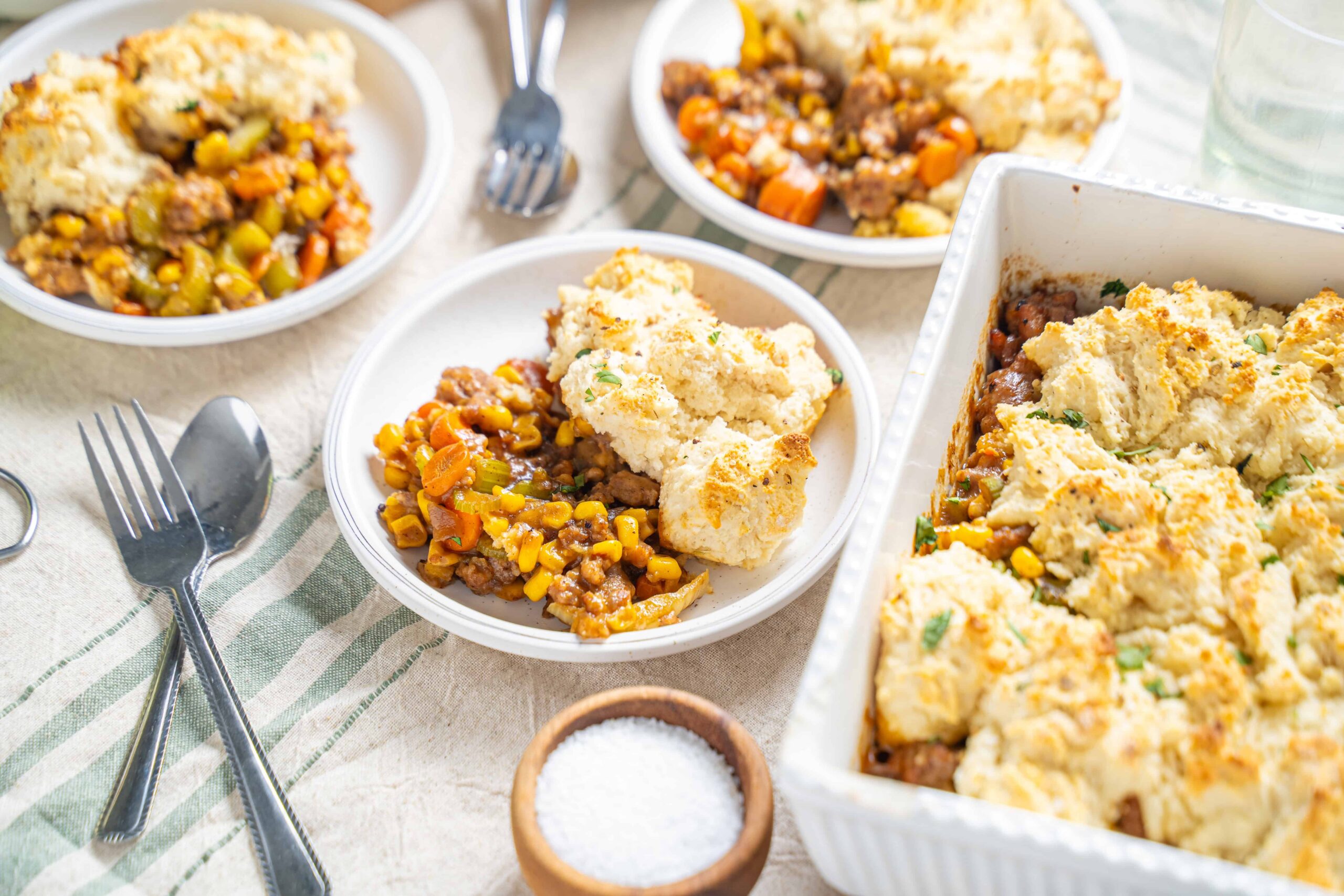 Hearty shepherd's pie with mashed potatoes, ground beef, mixed vegetables, and herbs served in baked casserole dishes. Perfect comfort food recipe for family dinners.