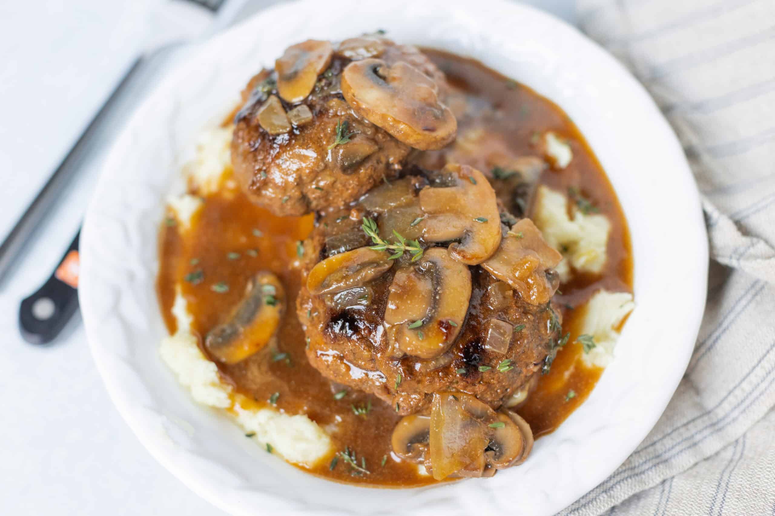Tender meatballs with mushroom gravy served over creamy mashed potatoes. This classic comfort food dish is perfect for cozy dinners and features savory flavors with fresh herbs.