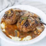 Savory meatballs with mushroom gravy served over creamy mashed potatoes on a white plate. Perfect comfort food dish for dinner or family meals, featuring tender meatballs topped with rich mushroom sauce.