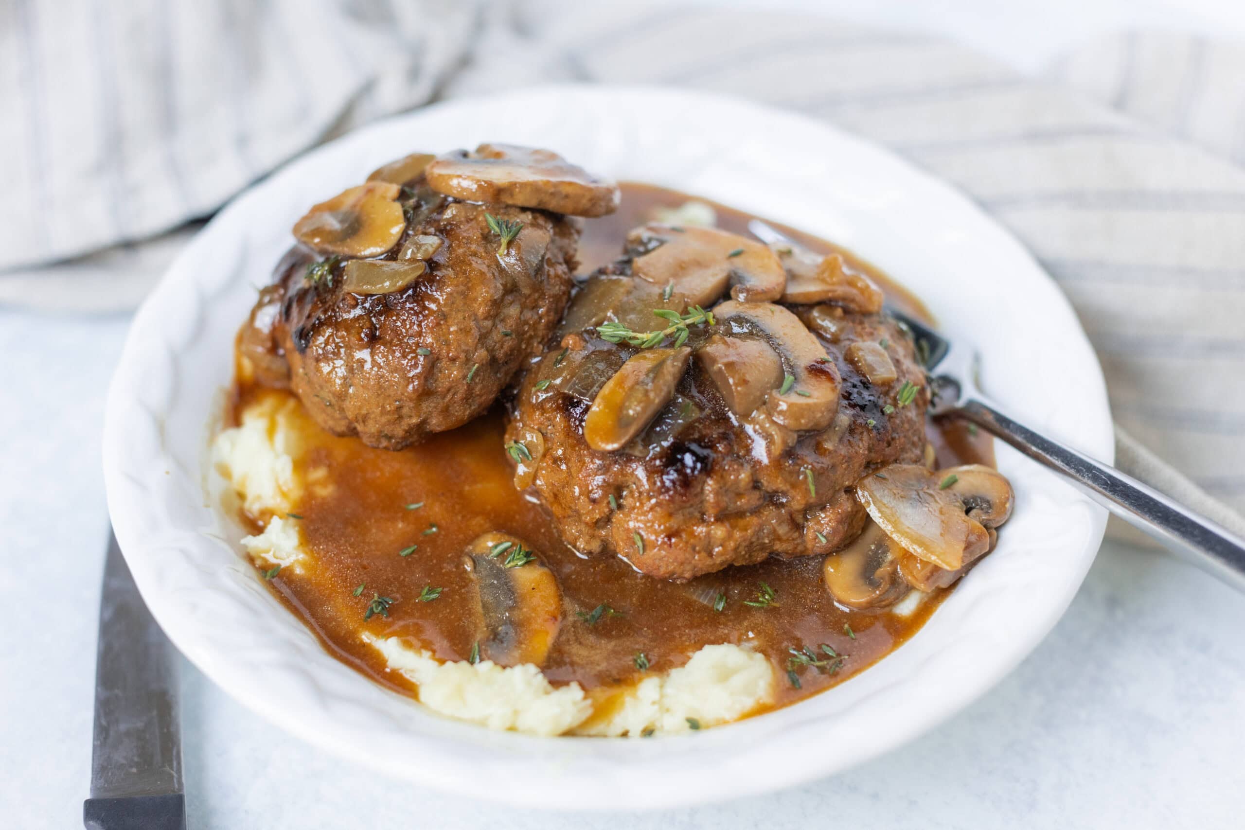 Savory meatballs with mushroom gravy served over creamy mashed potatoes on a white plate. Perfect comfort food dish for dinner or family meals, featuring tender meatballs topped with rich mushroom sauce.