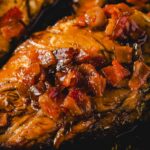 Succulent baked chicken breast topped with rich gravy and crispy bacon, served with a savory sauce and herbs for a flavorful, hearty meal. Perfect for dinner or weekend family gatherings.