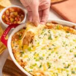 Creamy cheesy baked Mexican dip with melted cheese, ground beef, and fresh green herbs served with crispy tortilla chips.