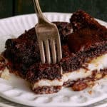 Rich, indulgent chocolate pecan pie with a flaky crust and gooey filling served on a decorative white plate. Perfect for dessert, bakers and chocolate lovers.