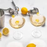 Refreshing lemon cocktails served in elegant champagne glasses with lemon twists, surrounded by fresh lemons and cocktail tools, perfect for summer drinks and party celebrations.