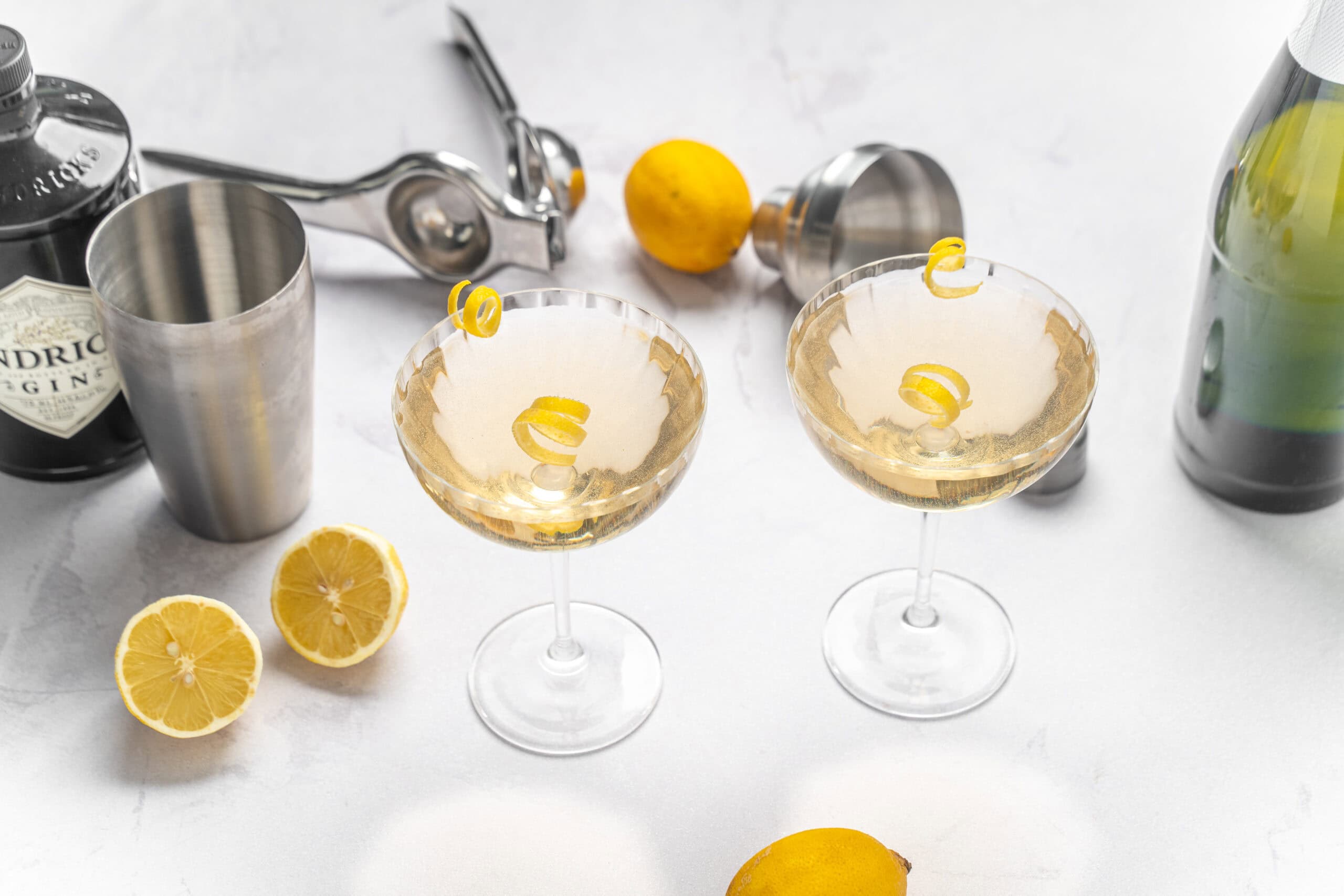 Refreshing lemon cocktails served in elegant champagne glasses with lemon twists, surrounded by fresh lemons and cocktail tools, perfect for summer drinks and party celebrations.