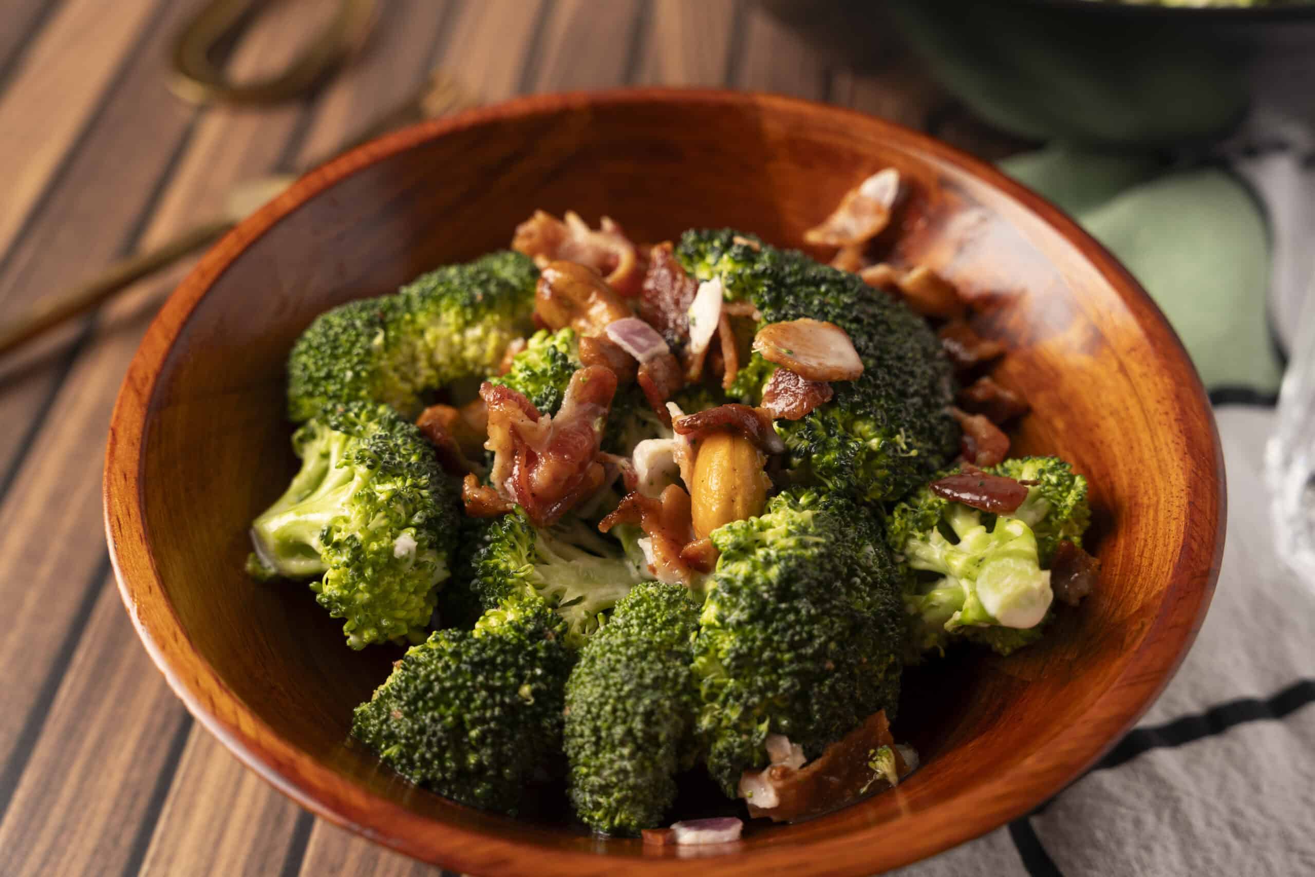 Steamed broccoli florets topped with crispy bacon pieces served in a wooden bowl, perfect as a healthy side dish or appetizer.