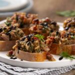 Savory stuffed bread topped with black sesame seeds, garnished with basil leaves on a white plate.