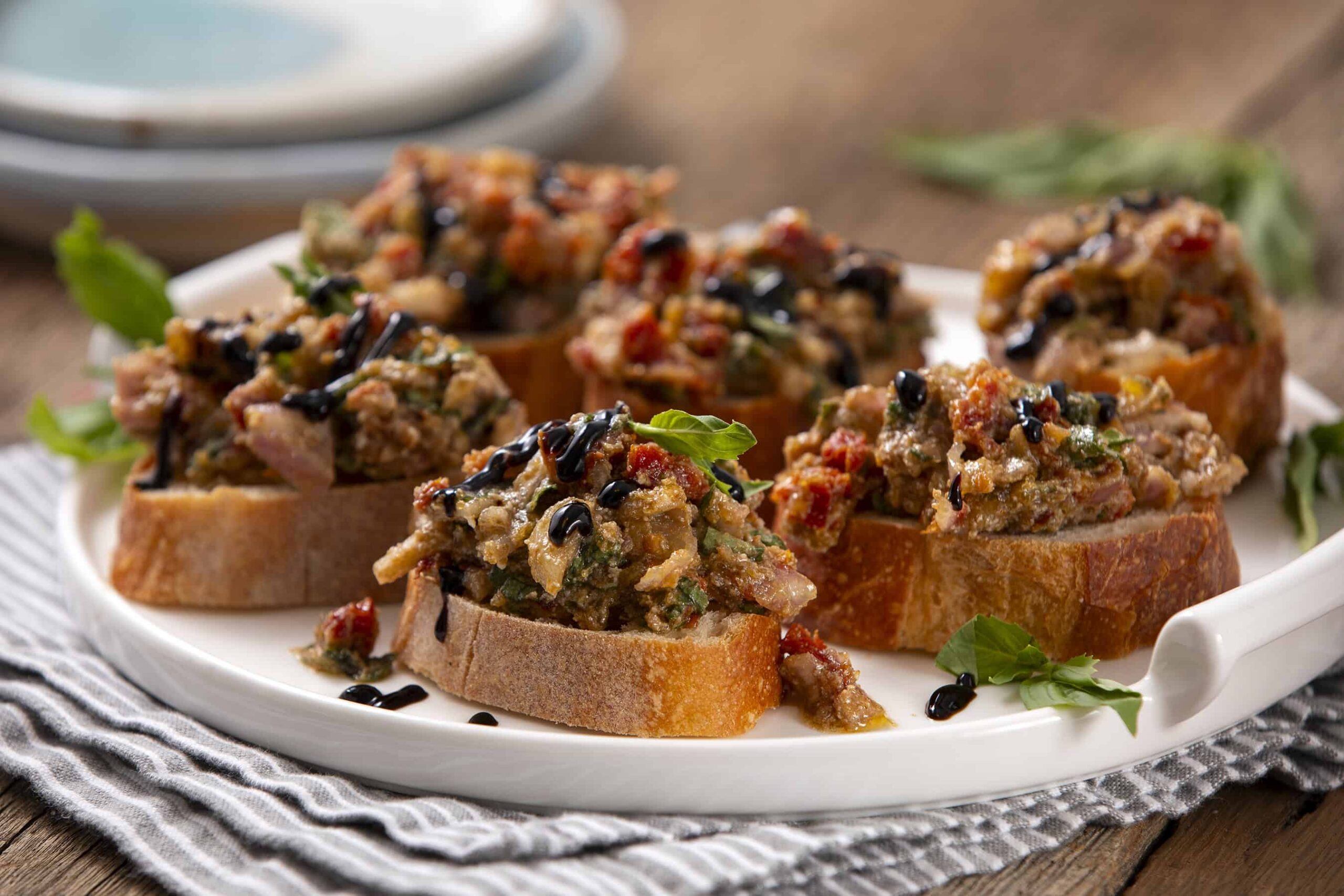 Savory stuffed bread topped with black sesame seeds, garnished with basil leaves on a white plate.