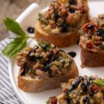 Savory mushroom and vegetable bruschetta topping served on toasted baguette slices garnished with basil and balsamic glaze. Perfect appetizer or party snack with fresh flavors.