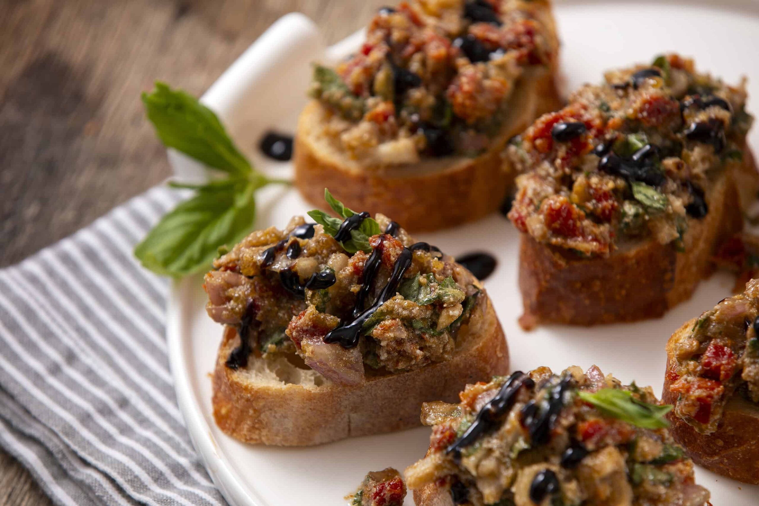 Savory mushroom and vegetable bruschetta topping served on toasted baguette slices garnished with basil and balsamic glaze. Perfect appetizer or party snack with fresh flavors.