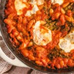 Savory baked Italian baked pasta with melted cheese, tomatoes, spinach, and beans in a cast iron skillet for a hearty, comfort food dinner.