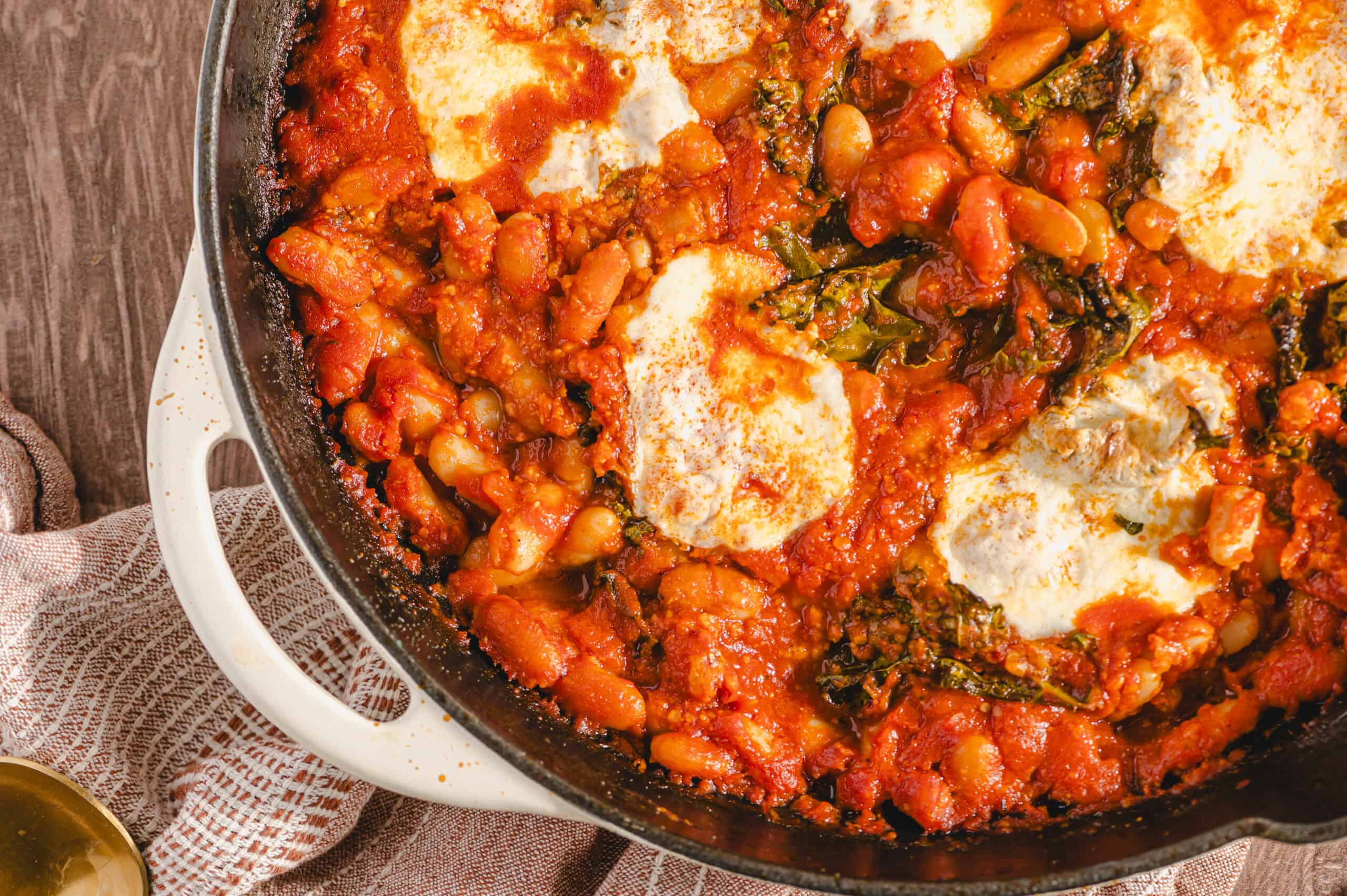 Savory baked Italian baked pasta with melted cheese, tomatoes, spinach, and beans in a cast iron skillet for a hearty, comfort food dinner.