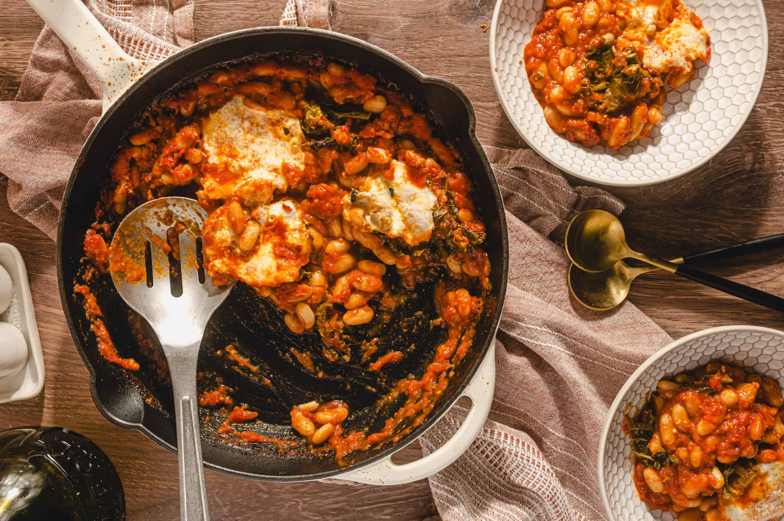 Savory baked white beans with tomato sauce and herbs served in a cast iron skillet, rustic wooden table setting, delicious comfort food with cheese melt, hearty and flavorful.