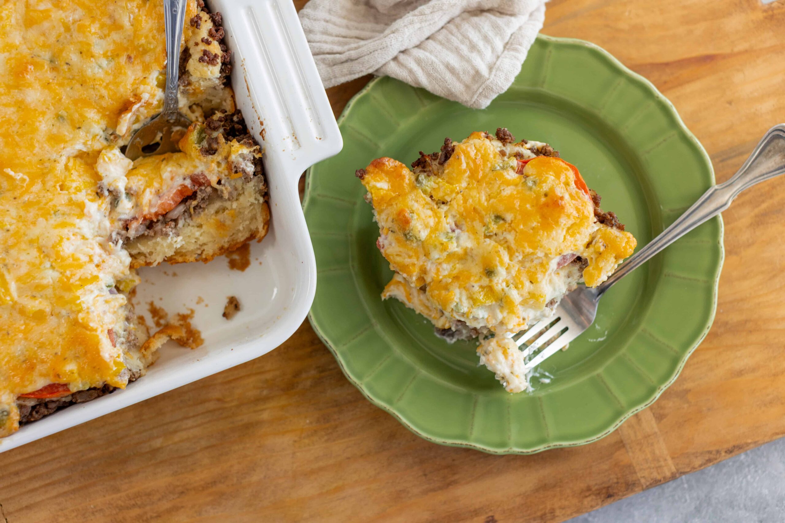 Creamy baked casserole with ground beef, vegetables, and melted cheese served in a green plate, ready to enjoy a comforting meal.