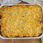 Golden baked cheesy casserole with ground beef and vegetables in a white baking dish.