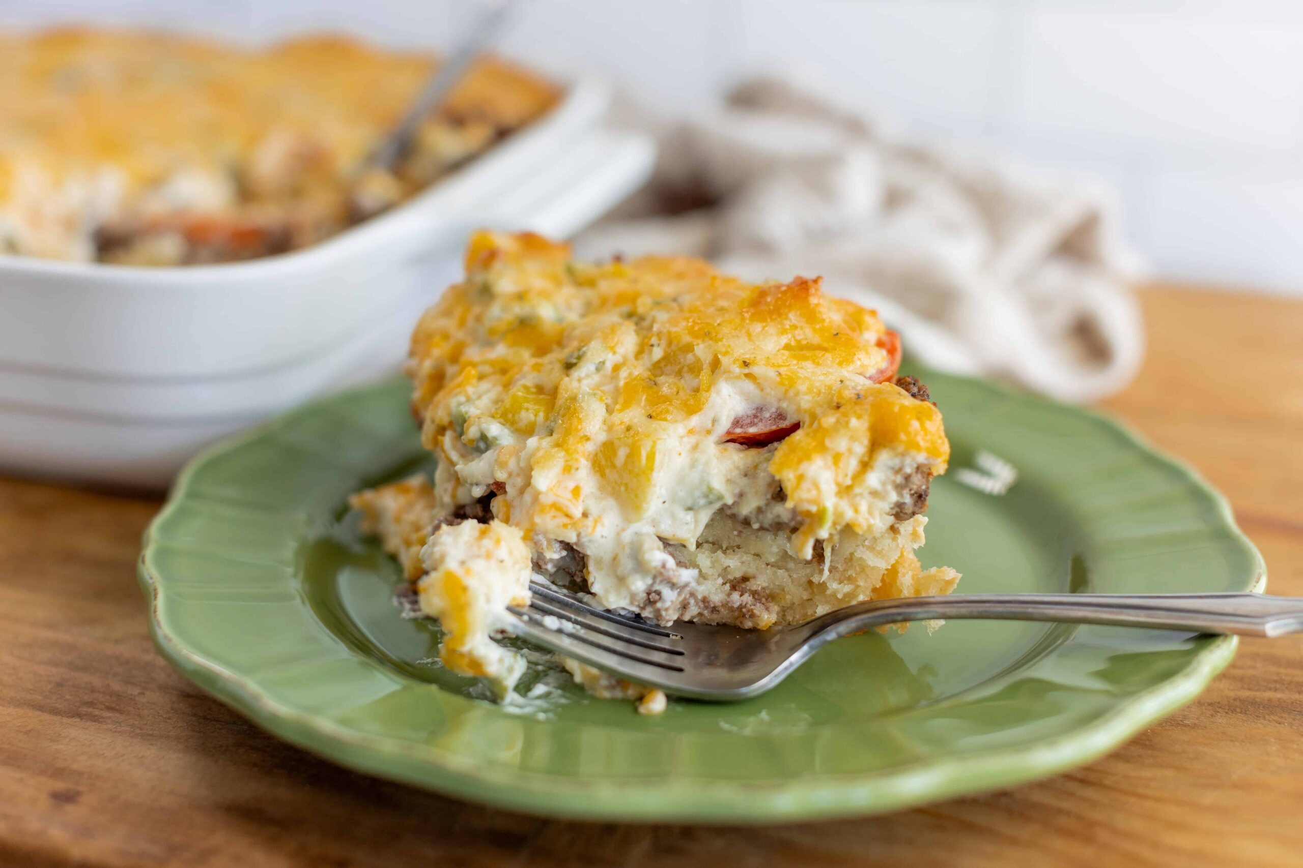 Cheesy breakfast casserole with eggs, cheese, and vegetables on a green plate, ready to serve. Perfect for brunch or family meals, easy baked egg casserole recipe with cheese, eggs, and veggies.