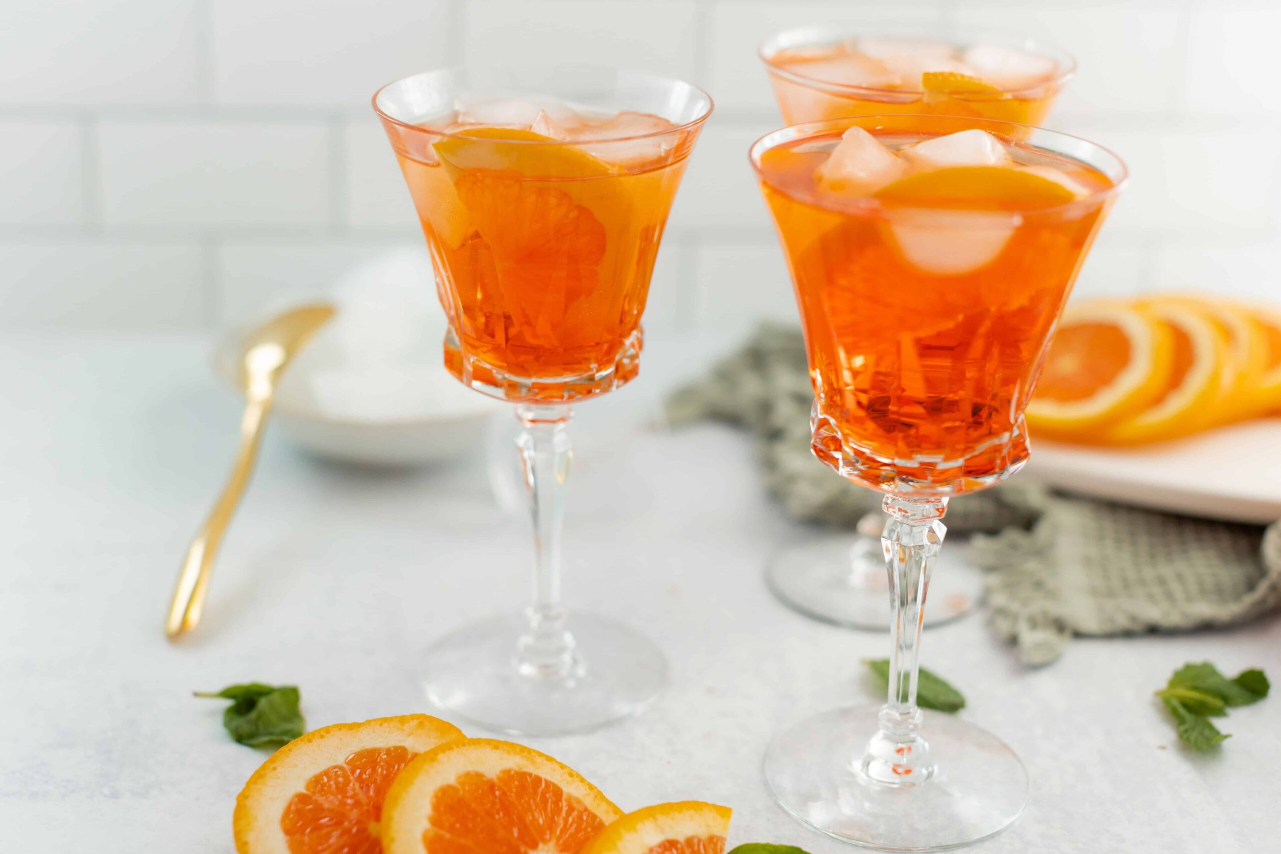 Bright orange citrus drinks served in elegant cocktail glasses with ice and orange slices, perfect for summer or brunch gatherings.
