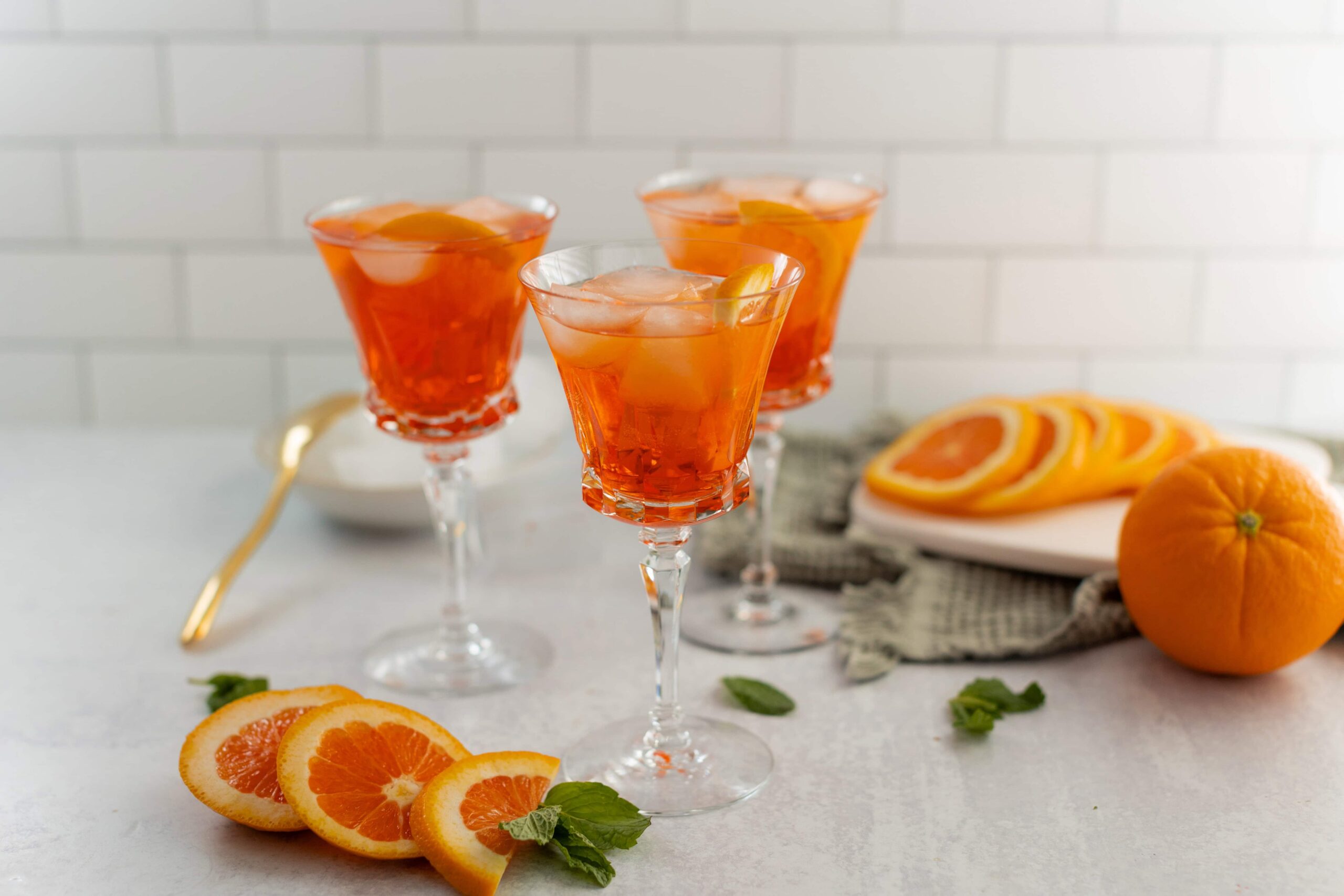Bright orange citrus cocktail with ice served in elegant crystal glasses, garnished with fresh orange slices and mint leaves, ideal for summer drinks and entertaining.