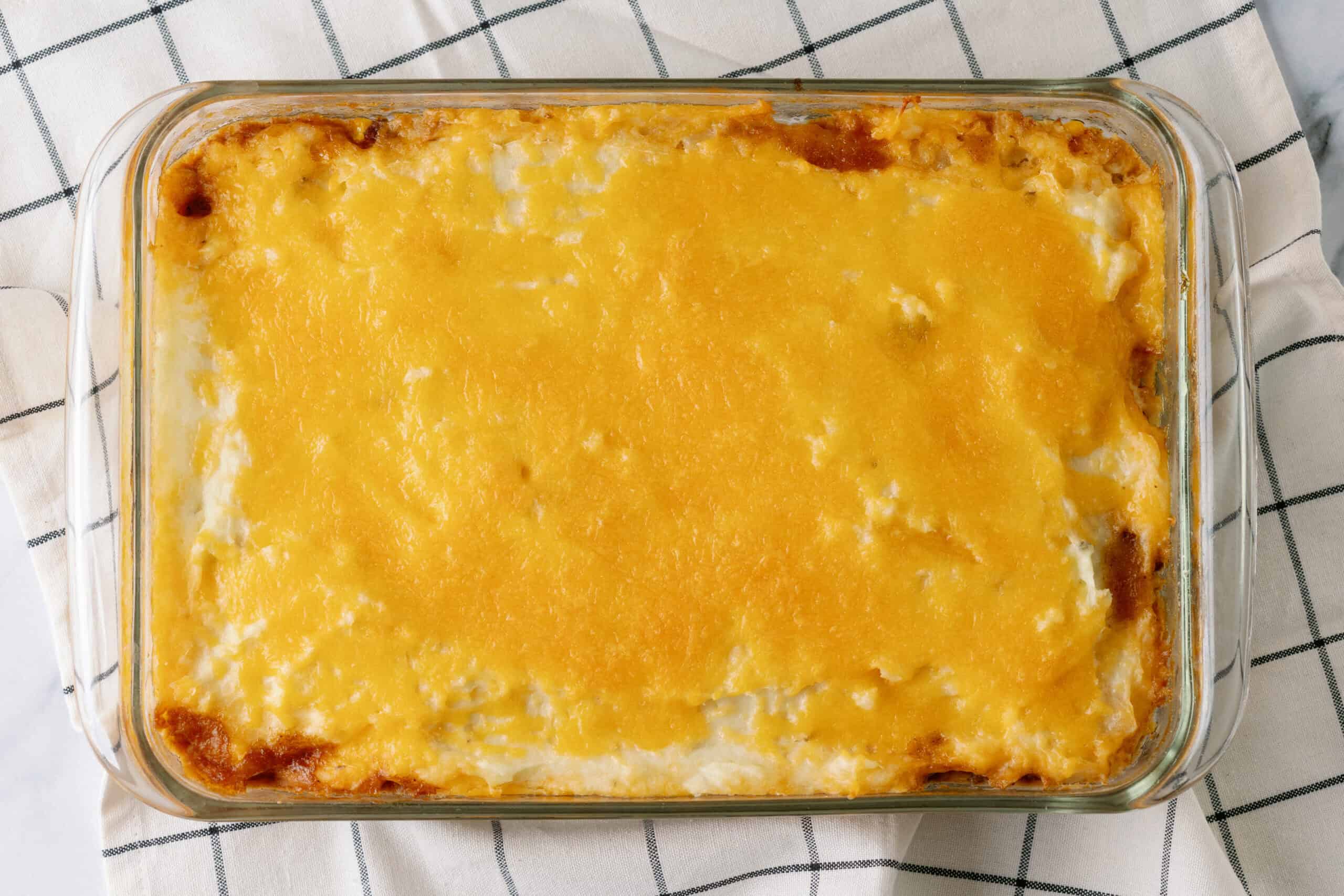 Golden baked cheesy casserole topped with melted cheese in a glass dish.