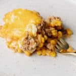 Creamy ground beef and corn casserole with melted cheese served on a white plate.