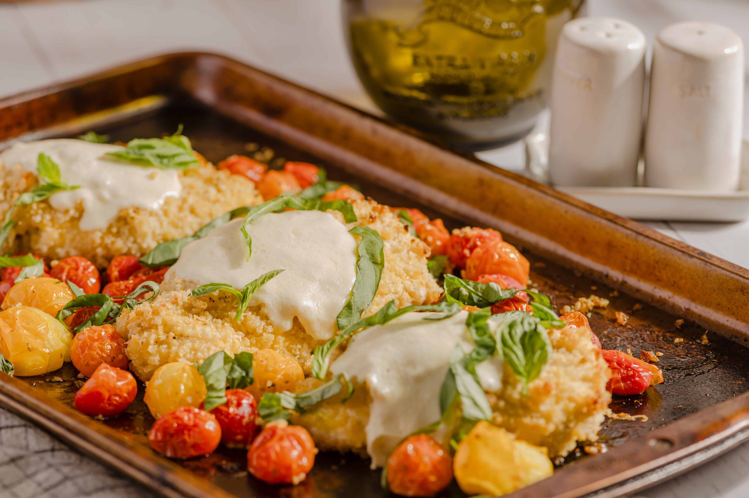 Spanakopita with cherry tomatoes and fresh herbs on a rustic baking tray.