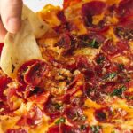 Golden, crispy pizza crust topped with pepperoni, herbs, and melted cheese, ready to be sliced and enjoyed. Perfect for snack or meal, showcasing authentic homemade pizza with fresh ingredients.
