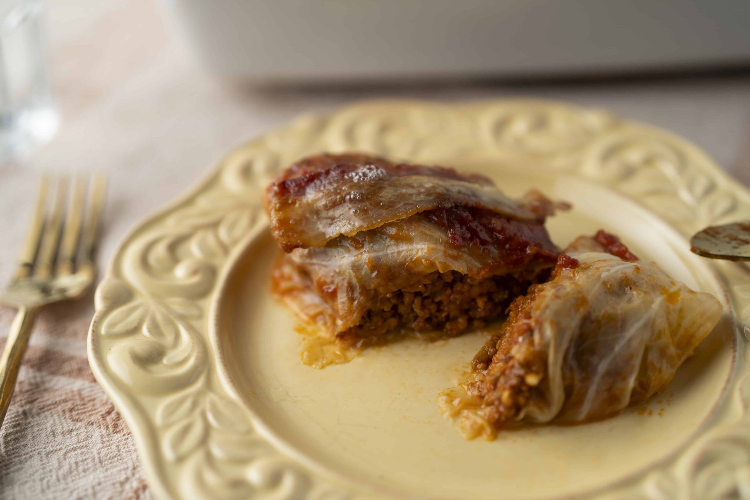 Ground meat casserole with melted cheese and tomato sauce on an ornate vintage plate, served as a savory baked dish, perfect for comfort food and family dinners.