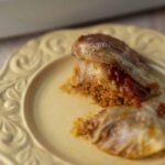 Slow cooker stuffed cabbage rolls with ground meat and tomato sauce served on an ornate ceramic plate.