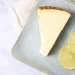 Creamy lemon cheesecake slice with lemon slices on a rustic ceramic plate, perfect for lemon dessert recipes and cheesecake lovers.
