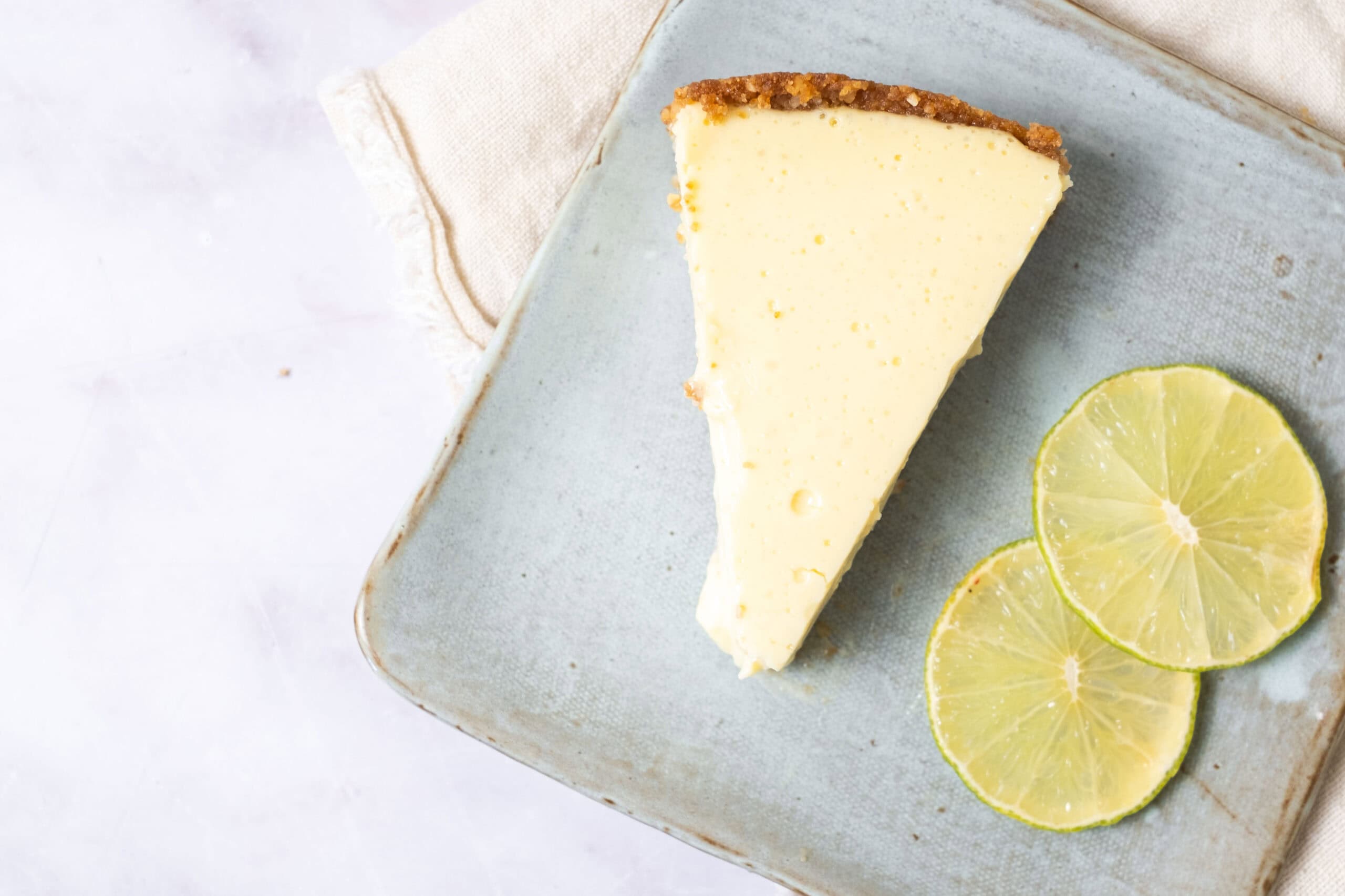 Creamy lemon cheesecake slice with lemon slices on a rustic ceramic plate, perfect for lemon dessert recipes and cheesecake lovers.
