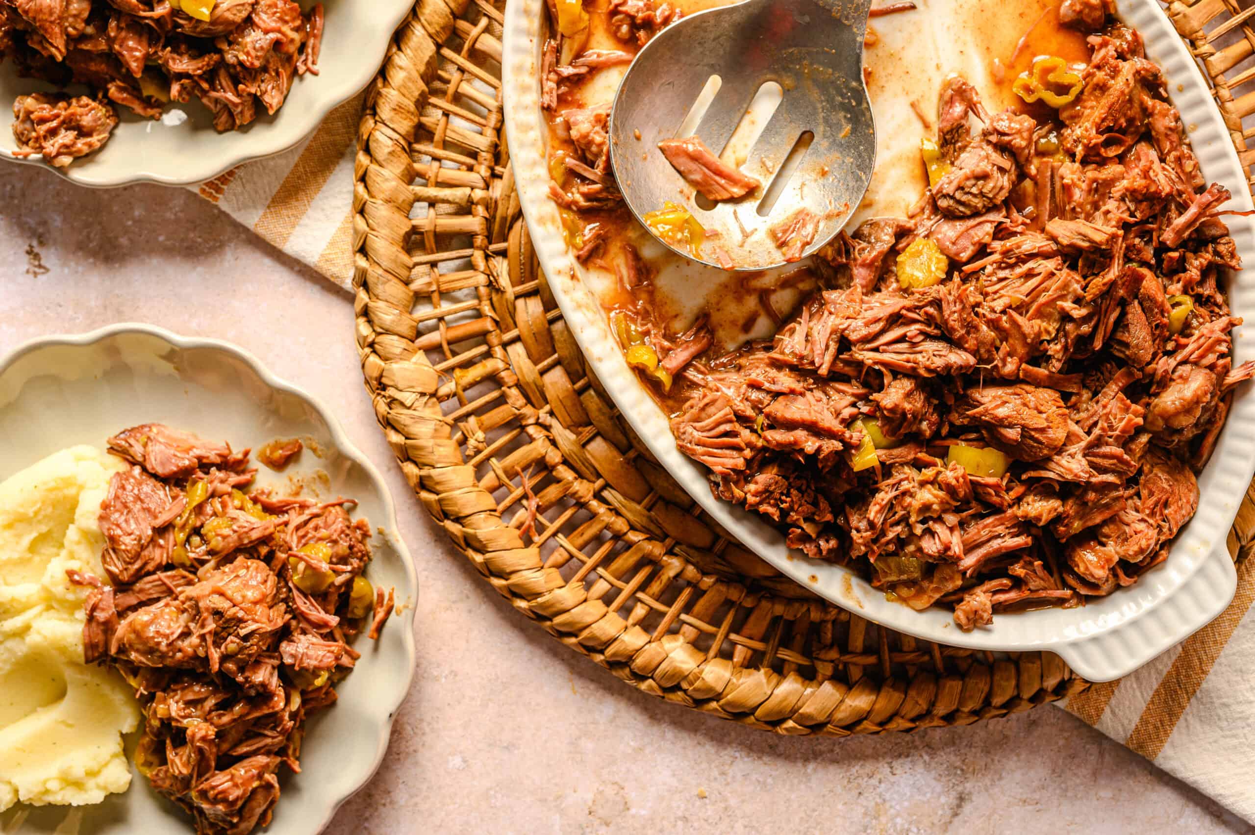 Tender shredded beef with vegetables in a creamy gravy served in a white ceramic baking dish on a rustic woven placemat. Perfect for hearty comfort food and family dinners.