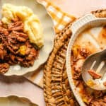 Shredded beef stew with mashed potatoes served on a white plate, close-up image of tender cooked meat with vegetables, hearty comfort food, delicious homemade stew, classic beef recipe, Hey Recipe.