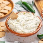 Cream cheese dip with jalapeno peppers and crispy crackers for snack or party platter. Fresh jalapenos adds a spicy kick to creamy, rich cheese spread, perfect for dipping or spreading on bread.