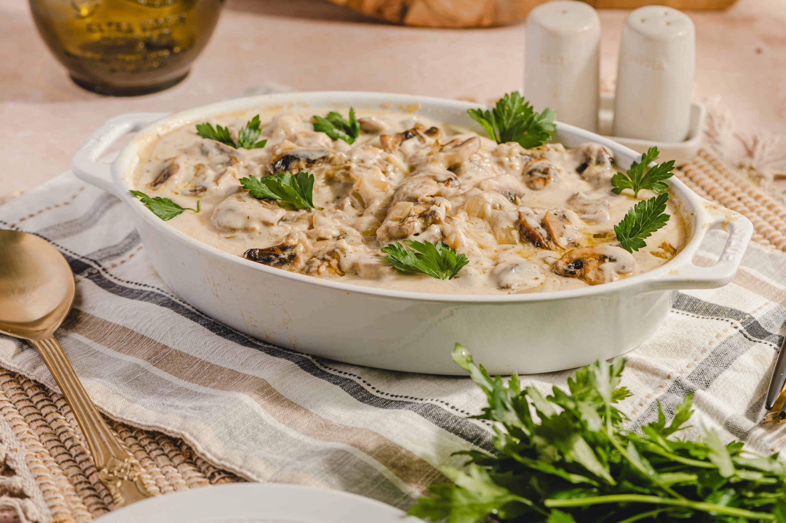 Savory creamy mushroom and chicken casserole garnished with fresh parsley in a white baking dish. Perfect comfort food dish with tender mushrooms and chicken in a rich sauce, served for family meals or special occasions.