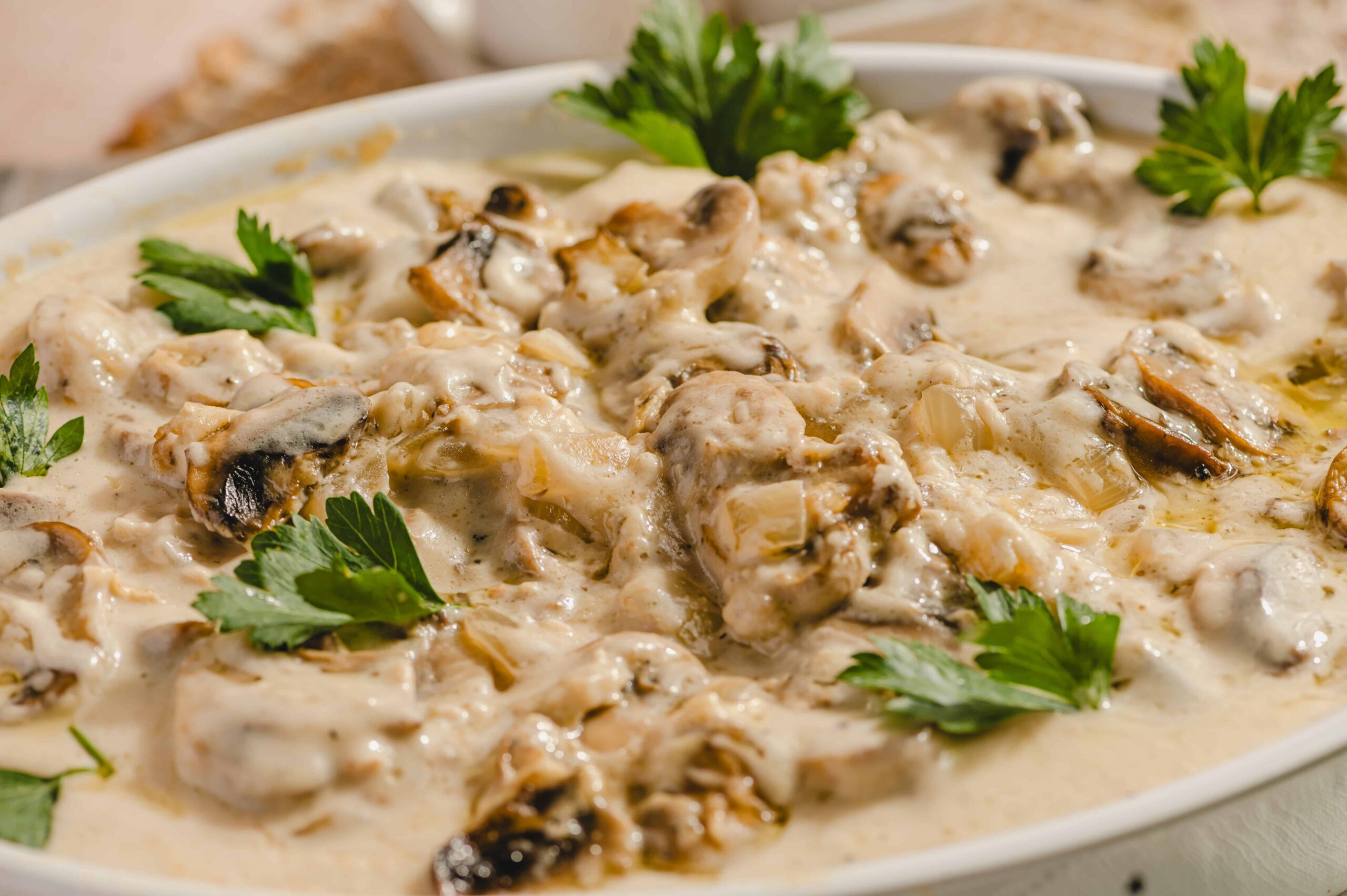 Creamy mushroom chicken casserole with fresh parsley garnish in a white serving dish, featuring tender chicken, sautéed mushrooms, and rich creamy sauce, perfect for hearty comfort food.